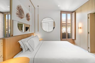 Detail of a single room with round mirror and wall-mounted TV