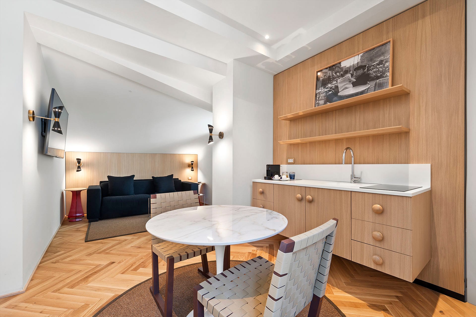 Detail of Prestige Quadruple Room with sofa and flat-screen TV, kitchenette with dining table